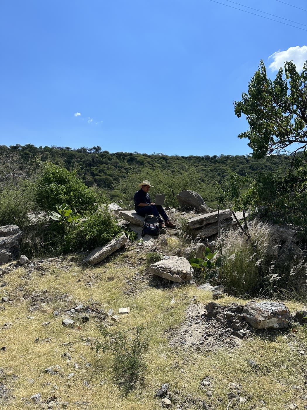 Original roadside photograph taken in Mexico - person sitting on rocks on a hillside